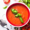 Bowl of tomato soup garnished with fresh basil leaves.