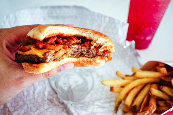 Wendy's burger half eaten with fries and drink