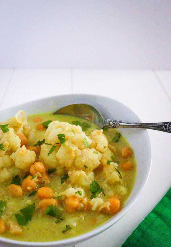 Bowl of chickpea and cauliflower coconut curry, garnished with chopped cilantro.