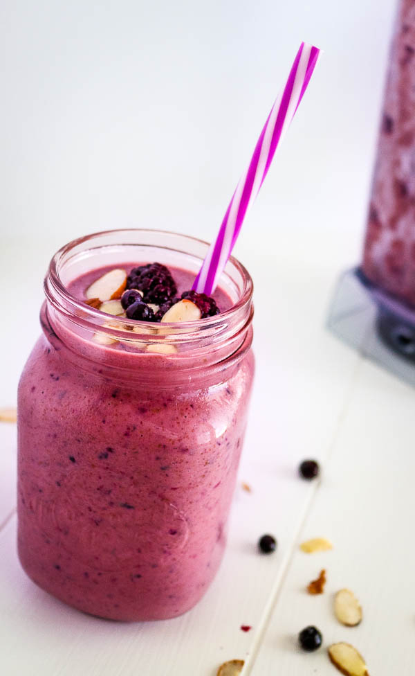 almond berry smoothie with straw and berry and sliced almond garnishes