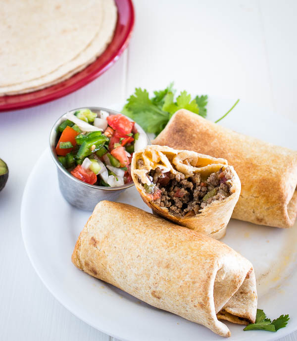 3 grilled stuffed burritos with salsa and one burrito bitten into