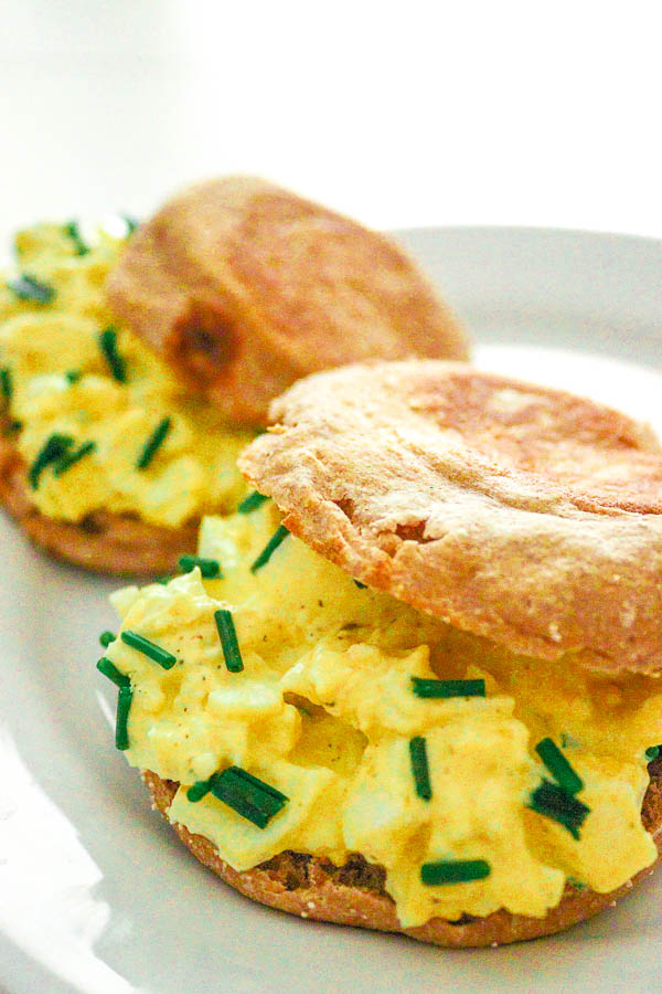 two egg salad sandwiches on english muffins, one behind the other