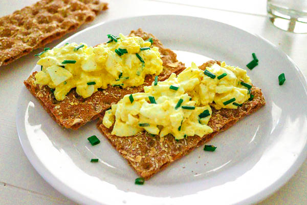 egg salad with chives on long wheat crackers, on a plate