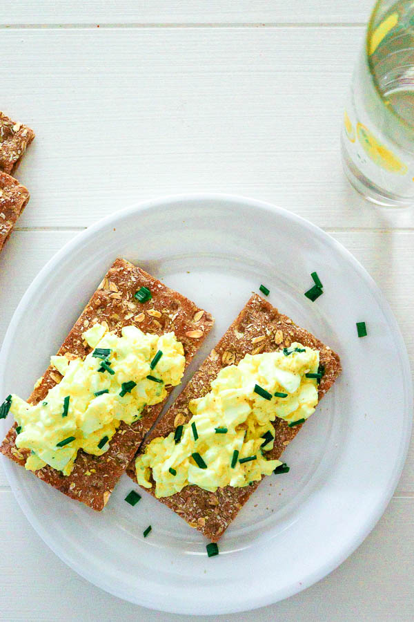 overhead view of egg salad with chives on long wheat crackers
