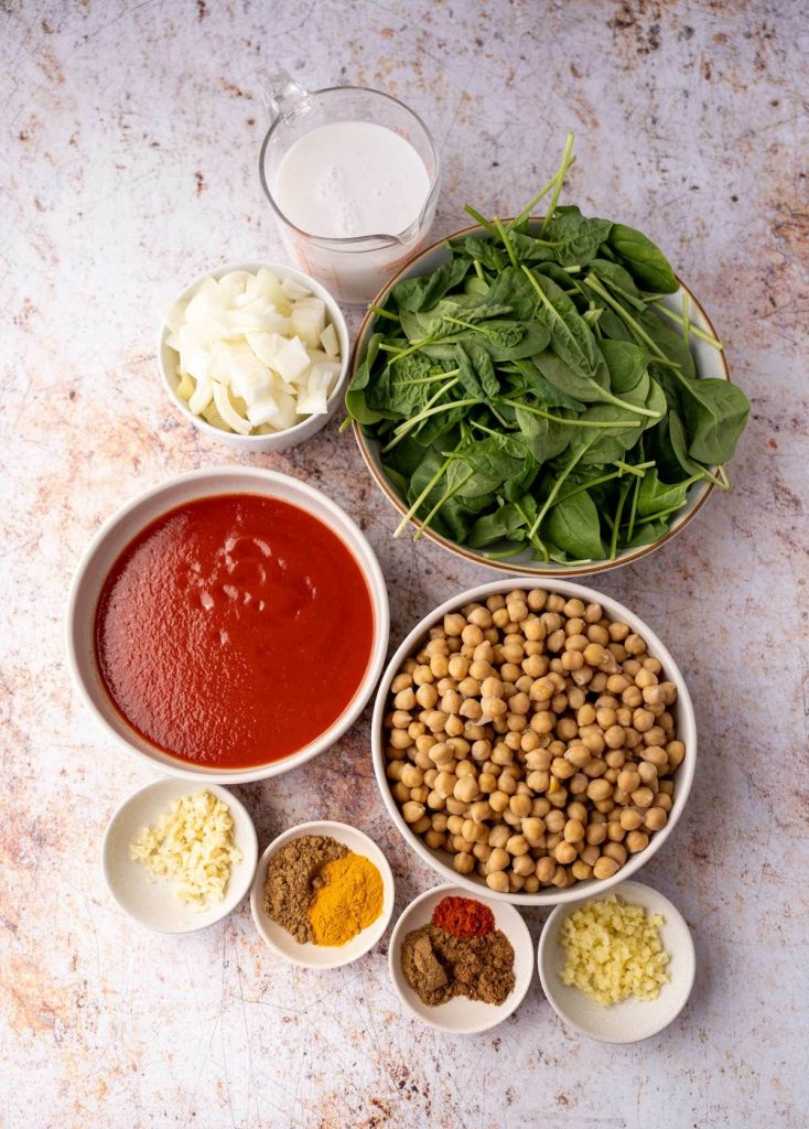 Overhead view of chickpea curry ingredients in separate bowls.