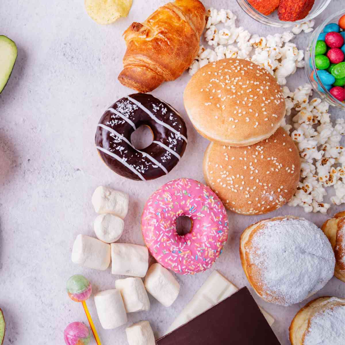 donuts, marshmallows, and other unhealthy foods on table.
