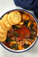 sausage kale soup in bowl, half lined with ritz crackers.