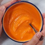 carrot soup in blue rimmed bowl with spoon.