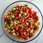 Chickpea salad mixed up in a glass bowl.